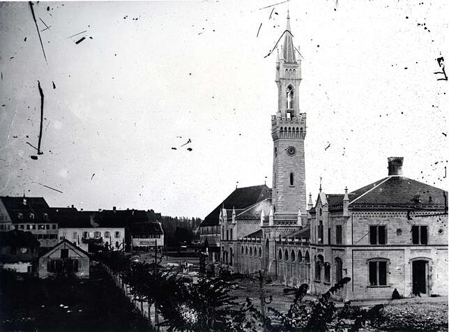 Der Bahnhofplatz nach 1863 und vor 1888, vermutlich um 1865. Links stand einst das Kapuzinerkloster, dahinter ist die Marktstätte. ...