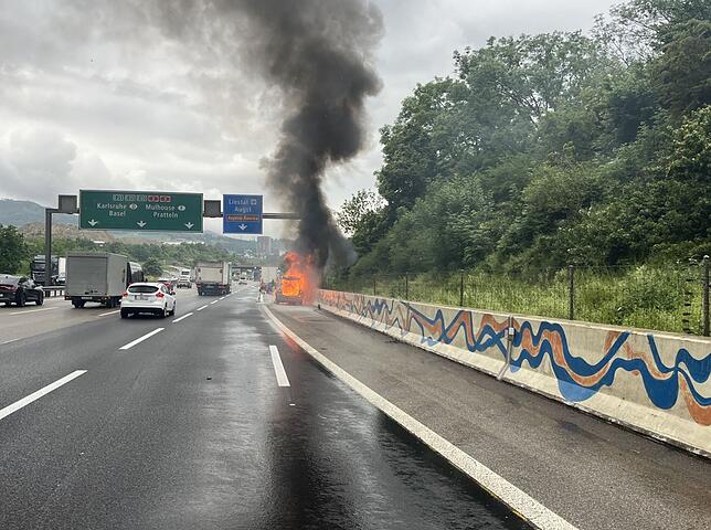 Ein brennendes Auto steht auf dem Pannenstreifen der A2 bei Augst.