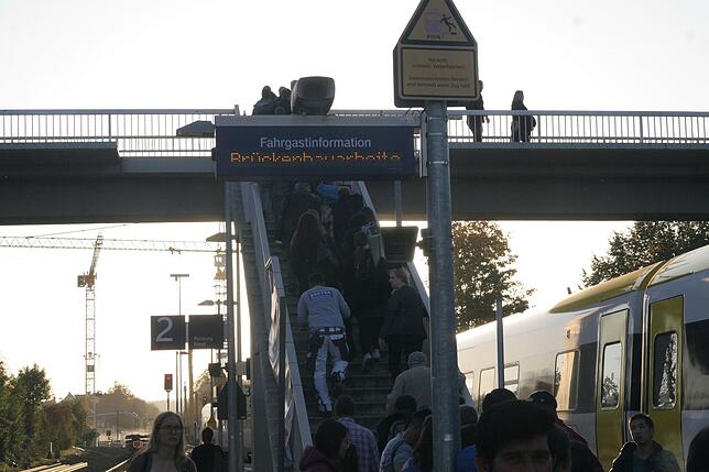 Abends in Albbruck: Der IRE kommt diesmal pünktlich an, Reisende marschieren zum Bus. Im Hintergrund die Kräne auf der Brückenbaustelle.