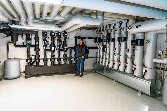 Facility Manager Sven Pofandt steht vor der Wärmepumpen-Anlage, die das gesamte Gebäude heizen, aber auch kühlen kann.