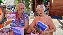 Beim Markt für Dorfvielfalt in Stadenhausen bieten Ines Zeller und Maria Theresia Rist die Festschrift für 6,50 Euro und die Postkarte ...