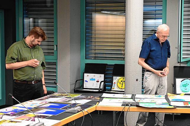 Julian Windmöller und Willi Zöller schauen die Bilder an und haben Klebezettelchen in der Hand, mit denen sie wie die anderen ...