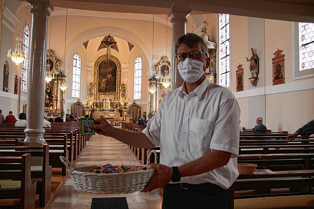 Pastoralreferent Franz-Josef Günther hält den Korb mit Weihwasserfläschchen, die an die Kirchenbesucher in Schwerzen verteilt wurden.