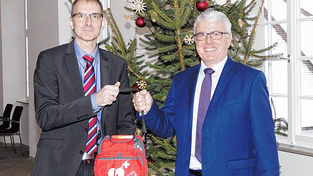 Bürgermeister Volker Frede (links) und Volksbank-Vorstand Werner Meichle zeigen einen der drei gespendeten Defibrillatoren, die in ...