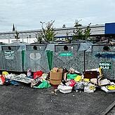 Vor den Glascontainern stapeln sich Säcke mit Restmüll.