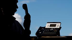 Ein Mann hält einen Telefonhörer in der Hand.