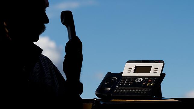 Ein Mann hält einen Telefonhörer in der Hand.
