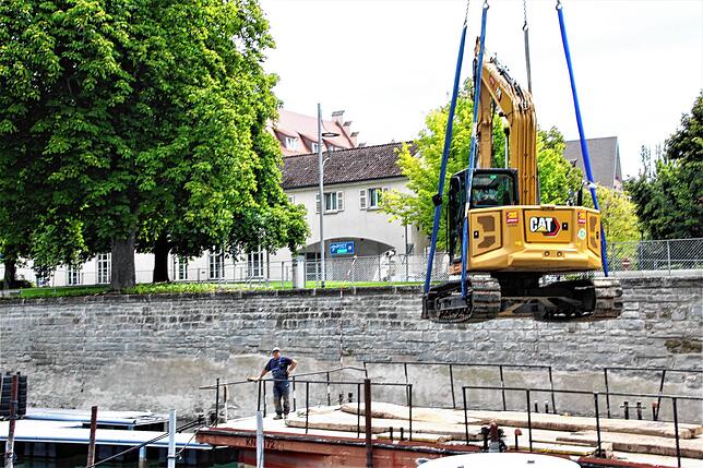 Die Bauarbeiten am Mantelhafen verzögern sich. Wegen unvorhergesehener Bodenbeschaffenheit muss der Bagger wieder mit dem Kran ans Ufer ...