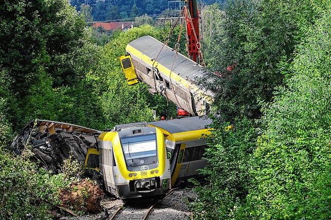 Mit einem Kran wird an der Unfallstelle, an der ein Regionalzug entgleist ist, am 28. Juli ein Waggon angehoben.