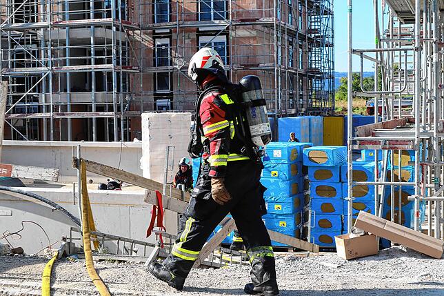 Ein Feuerwehrmann geht am Ende des Einsatzes an aufgestapeltem Baumaterial vorbei.