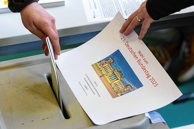 Eine Frau wirft ihren Wahlzettel zur Bundestagswahl in die Wahlurne. Am Sonntag findet die spannende vorgezogene Wahl zum 21. Deutschen ...
