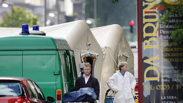 Ein Bestatter schiebt eine Trage mit einer Leiche von einem Tatort in Duisburg. Sechs Menschen wurden 2007 in der Stadt vor einer ...