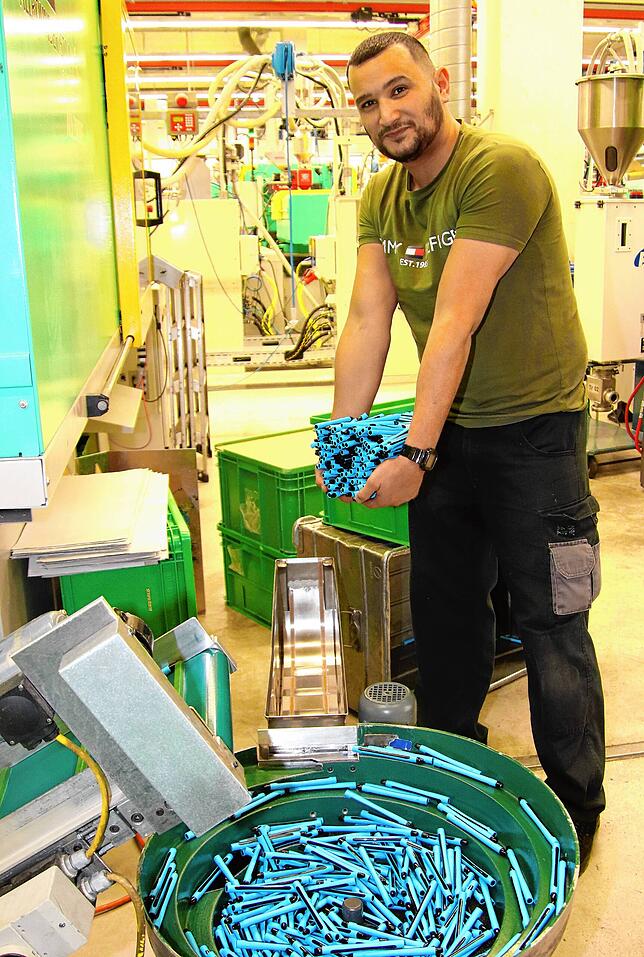 Murat Yavuzyilmaz hebt die Kunststoffhüllen für den Slider Rave aus der Spritzgussmaschine. In ihr werden zwei unterschiedliche ...