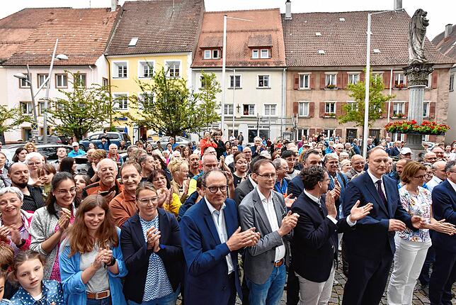 Vor dem Rathaus haben sich viele Menschen eingefunden, um den neuen Bürgermeister zu feiern.