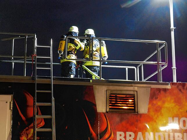 Zwei Feuerwehrleute dringen über das Dach in ein brennendes Zimmer ein.