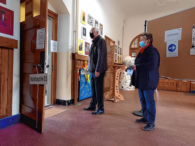 Zwei Wählende warten vor einem Klassenraum der Hausherrenschule darauf, ihre Kreuzchen zu setzen.