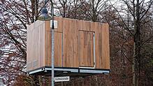 In luftiger Höhe schwebt das erste Bauteil , transportiert von einem Kran.