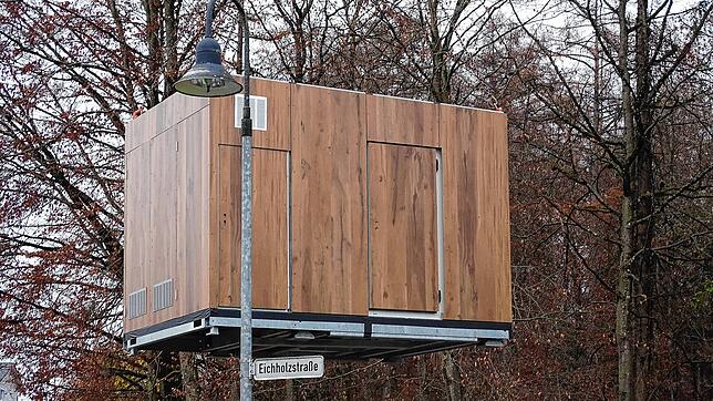 In luftiger Höhe schwebt das erste Bauteil , transportiert von einem Kran.