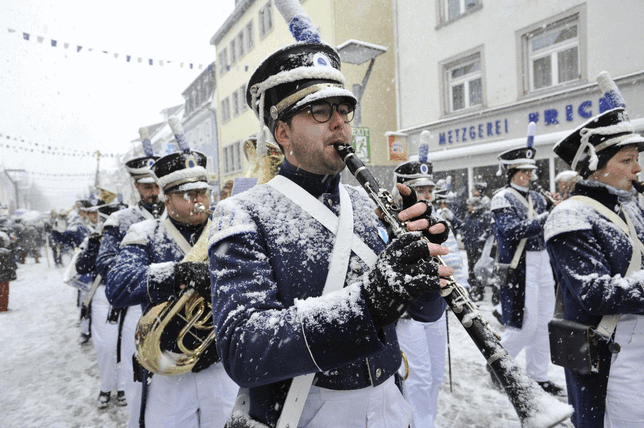 Villinger Narren ziehen im Jahr 2018 durch die schneebedeckte Stadt.