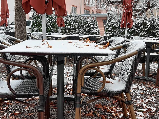 Schnee und Herbstlaub liegen auf dem Tisch einer Gartenwirtschaft in Waldshut.