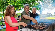 Von links: Nurhayat und Cengiz Aktas wenden gemeinsam mit Koch Caner Fisch und Köfte auf dem Grill.
