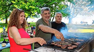 Von links: Nurhayat und Cengiz Aktas wenden gemeinsam mit Koch Caner Fisch und Köfte auf dem Grill.