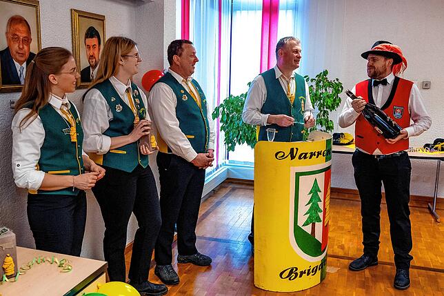Patrick Fleig von der Gayser-Gilde Obereschach übergibt seiner Paten-Zunft Brigachtal eine extra große Flasche Mumm-Sekt.