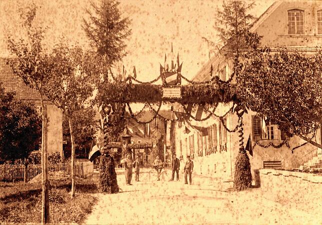 Das Ehrentor am Ortseingang in der Birretstraße im Jahre 1894. Rechts erkennt man das Einsiedlerhaus – heute Cafe Central und ...