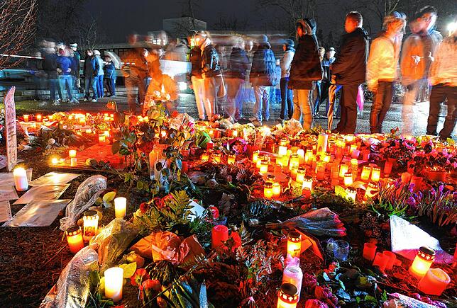 Trauernde Schüler und Bürger des Ortes Winnenden stehen nahe der Albertville-Realschule (im Hintergrund) vor zahllosen Blumen und ...