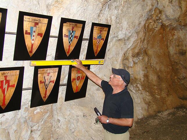 Walter Paape misst nochmal nach. Im unteren Bereich der Burghöhle sind die neu angebrachten Wappen der Neutempler zu sehen.