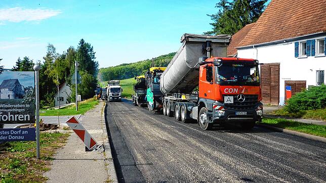 Etliche schwere Fahrzeuge sind im Einsatz, als am Pfohrener Ortseingang der Asphalt ausgebracht wird. Mit einem neuen Belag versehen ...