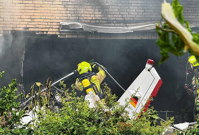 Die Feuerwehr arbeitet an der Absturzstelle, nachdem ein Flugzeug in ein Wohnhaus gestürzt ist.