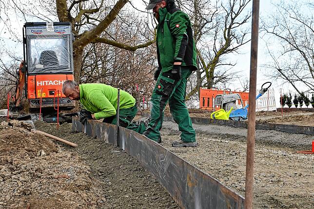 Marc Schüler und Pavel Marocico setzen eine neue Stahlkante für die terrassenförmig angelegte Parkanlage.