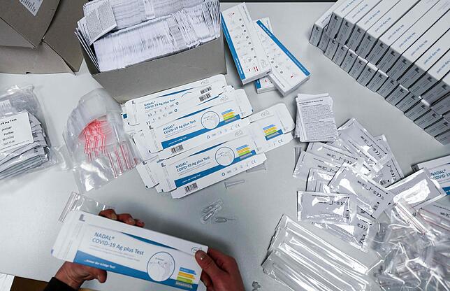 Viele Antigen-Schnelltests liegen ausgepackt auf einem Tisch.