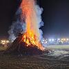 Ein riesiger Holzhaufen brennt am Freitag, 5. Januar 2024, auf der Wiese bei Horheim, 400 Traktoren stehen drum herum.
