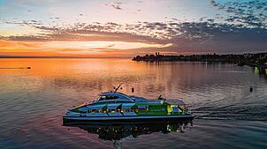 Katamaran Fridolin verlässt bei Sonnenuntergang den Hafen in Friedrichshafen.