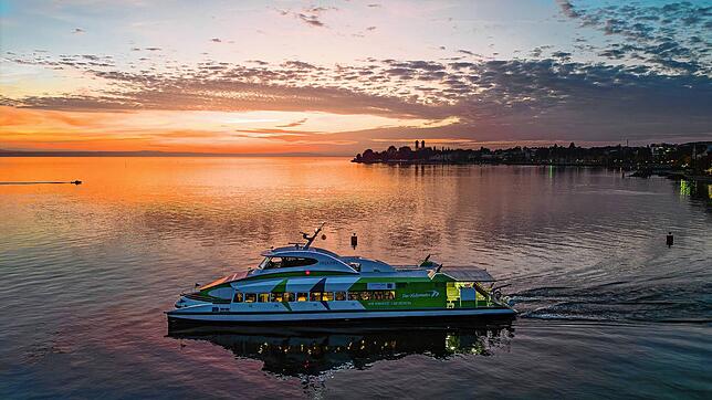 Katamaran Fridolin verlässt bei Sonnenuntergang den Hafen in Friedrichshafen.