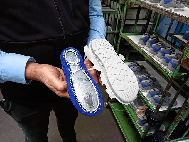 Ein Ricosta-Schuh, mit und noch ohne Sohle. Dass überflüssige Material am Rand der Sohle wird in einem späteren Arbeitsschritt entfernt.