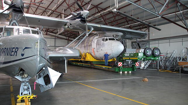 Blick in die Halle "Whisky" am Airport Friedrichshafen: Es scheint, als breite die Dornier Do-24 ATT (links) ihre schützende Tragfläche ...