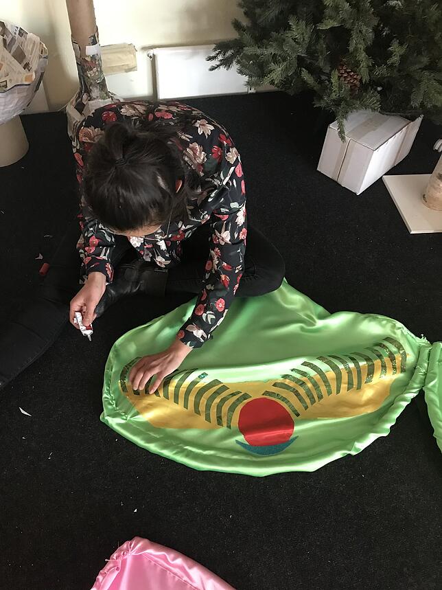 Mit einem Kleber in der Hand arbeitet Selina Yener an einem grünen Schmetterlingsflügel.