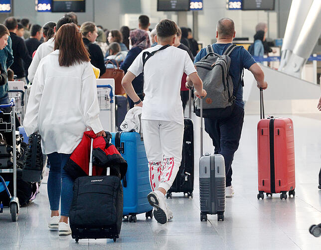 Urlauber stehen an einem Check-In-Schalter am Flughafen an.