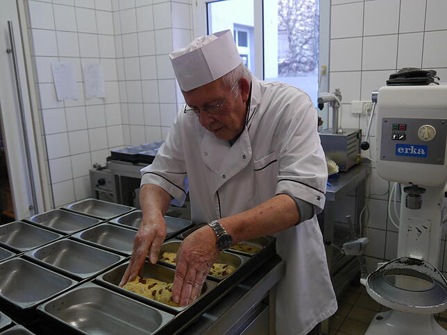 Heinz-Martin Sapel verteilt den Teig für die Christstollen in die Backformen.