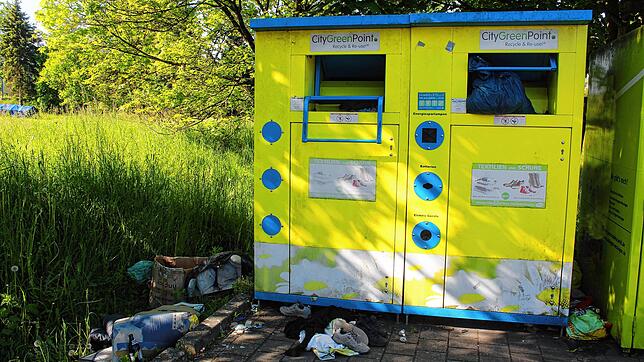 Vor dem Wertstoff-Container liegen einige Dinge wie Schuhe und Oberbekleidung, die eigentlich in den Container gehören. Doch auch ...