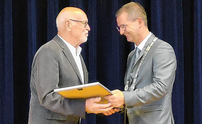 Bürgermeister Patrick Stärk überreicht Klaus-Peter Minge die Urkunde zur Bürgerehrung.