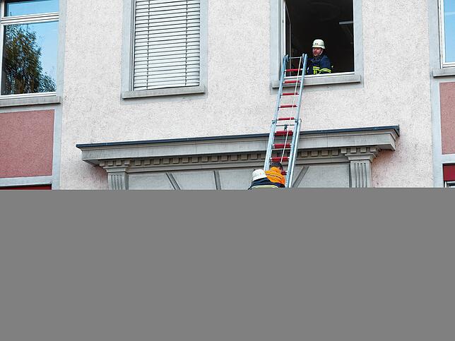 Gesichert an einem Seil und durch einen Feuerwehrmann geht es auf der Schiebeleiter nach unten.