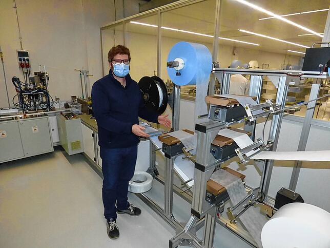 Geschäftsführer Michael Hitz zeigt die automatische Produktionslinie einer Maschine zur Herstellung von Mundschutzmasken im Betrieb in ...