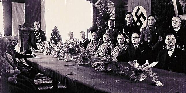 Ernste Mienen beim Gruppenbild zur Zwangseingemeindung am 1. August 1934 im Konstanzer Rathaus, unter ihnen am Tischende (stehend mit ...