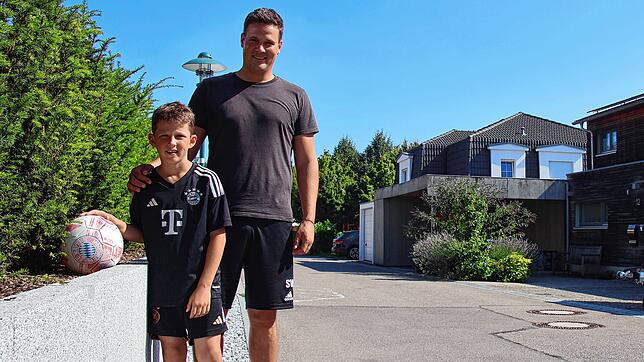 Elias Willibald (links) und sein Vater Sebastian Willibald, der Fußball und die Hecke. Hinten rechts: Der betroffene Carport.