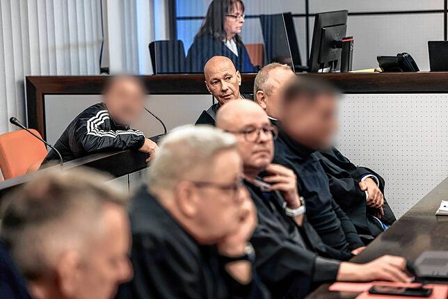 Der Hauptangeklagte (hinten, links) spricht im Gerichtssaal mit seinem Verteidiger Oliver Doelfs (hinten, rechts), während vorne ein ...