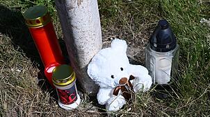 Menschen haben Kerzen und einen Teddybären an der Unfallstelle abgestellt.